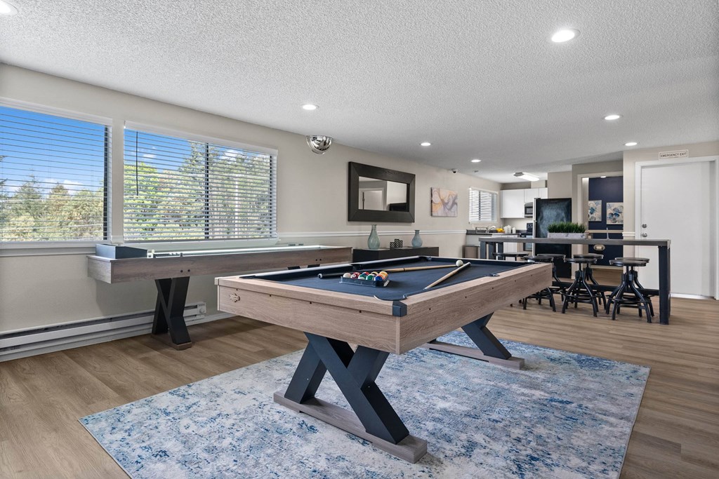 A pool table in a room with a view of trees outside the window.