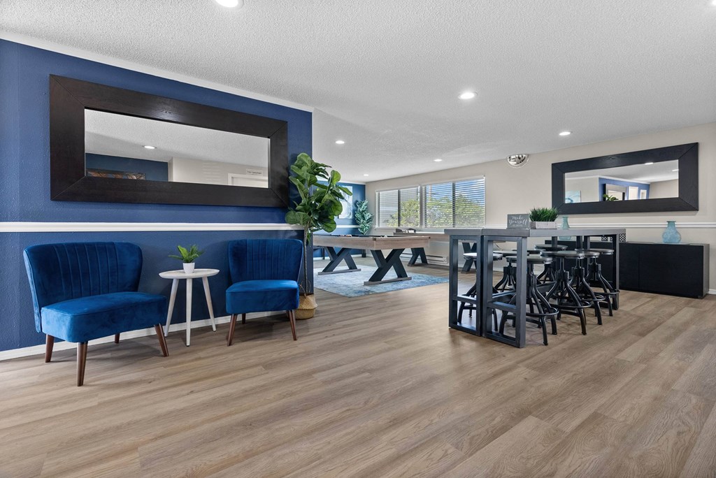 A living room with blue chairs and a wooden floor.