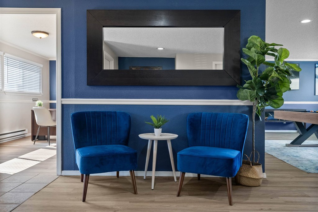 Two blue chairs are placed in front of a mirror.