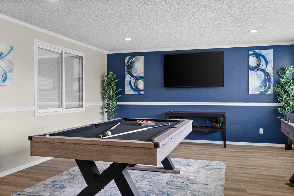 A pool table in a room with blue walls and a flat screen TV.