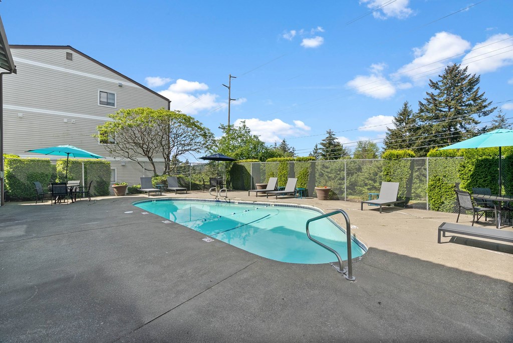 A small pool in a backyard with a table and chairs.