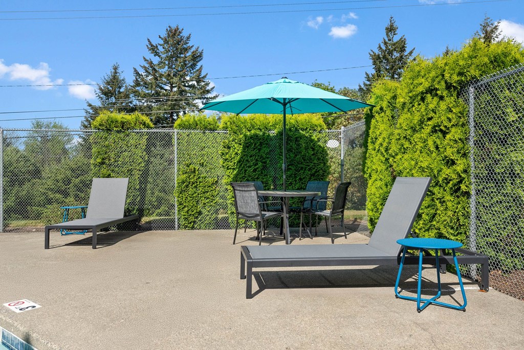 A patio with a table, chairs, and an umbrella.
