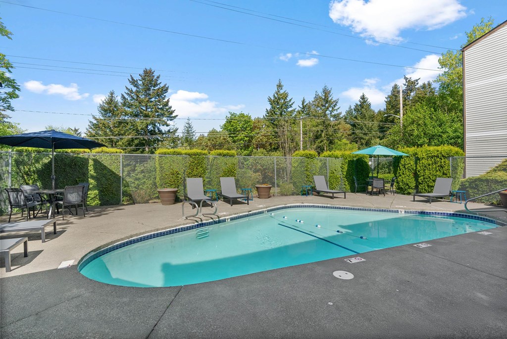 A small pool surrounded by a fence and trees.