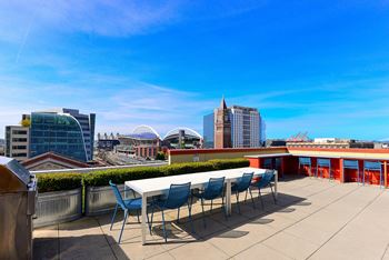 a table and chairs on a roof terrace with a view of the city at Icon Apartments, Seattle, WA