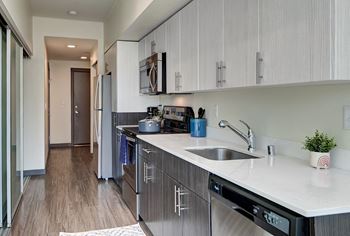 a kitchen with stainless steel appliances and white counter tops and a sink at Icon Apartments, Seattle, WA, 98104