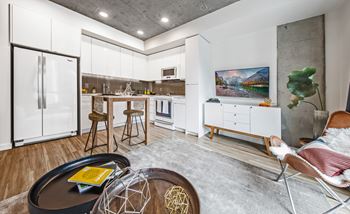 A modern kitchen with a refrigerator, stools, and a dining table.