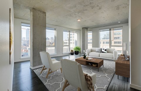 A modern living room with a white sofa and a large window overlooking the city.