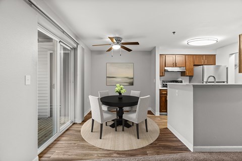 A dining room with a table set for two and a ceiling fan.