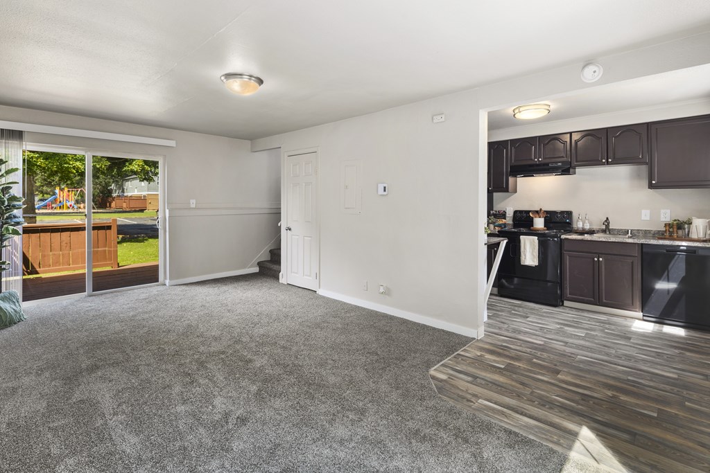 A spacious living room with a kitchen area in the background.
