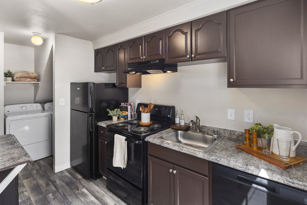 A kitchen with black appliances and brown cabinets.