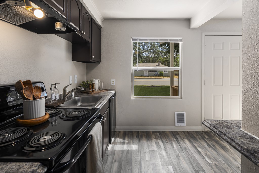 A kitchen with a black stove top oven and wooden handles.