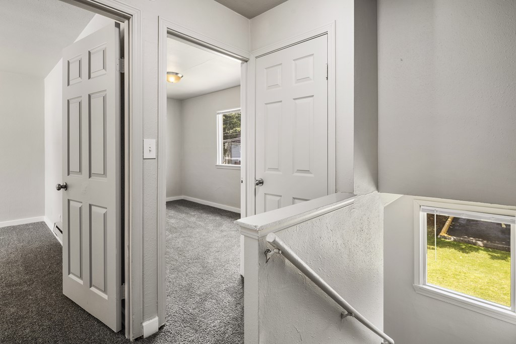 A white door is open to a room with a carpeted floor.