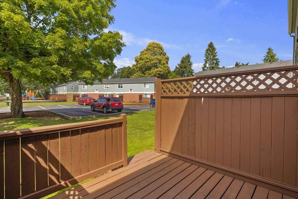 A wooden deck with a lattice fence and a tree in the background.