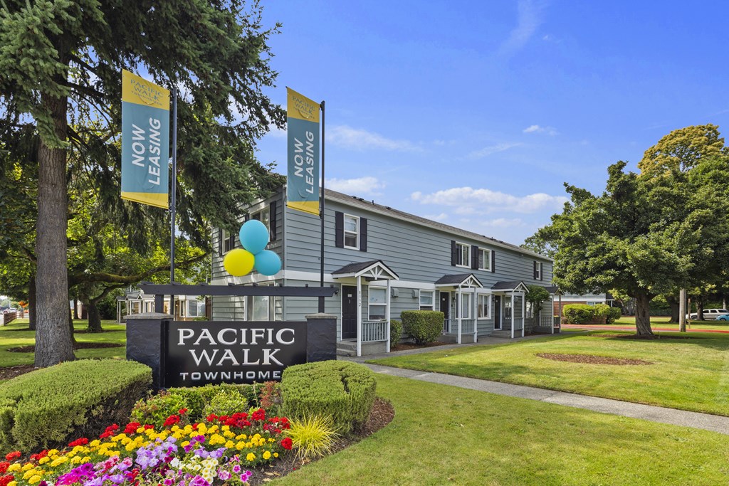 A sign for Pacific Walk Townhome is in front of a building with balloons.