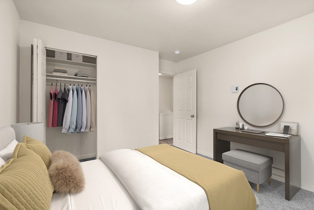 A bedroom with a bed, desk, and wardrobe.