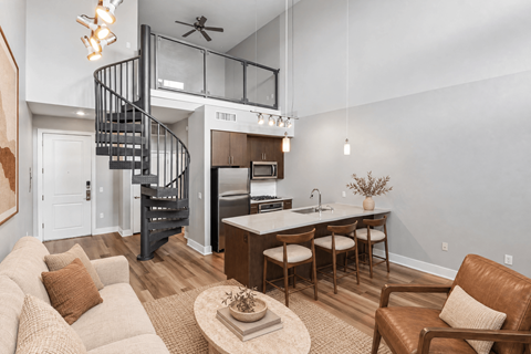 A living room with a spiral staircase and a kitchen area.