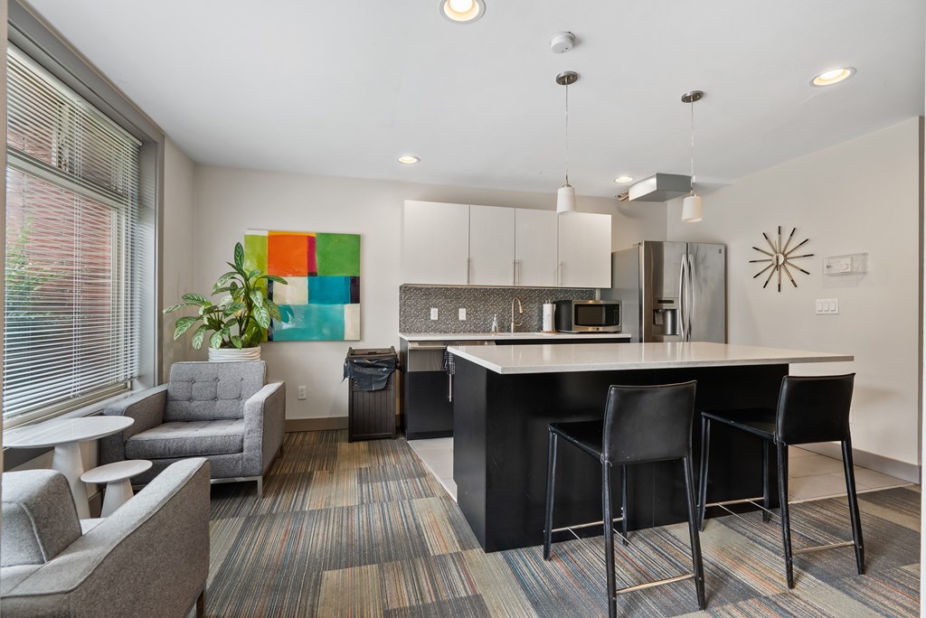 A modern kitchen with black bar stools and a white countertop.