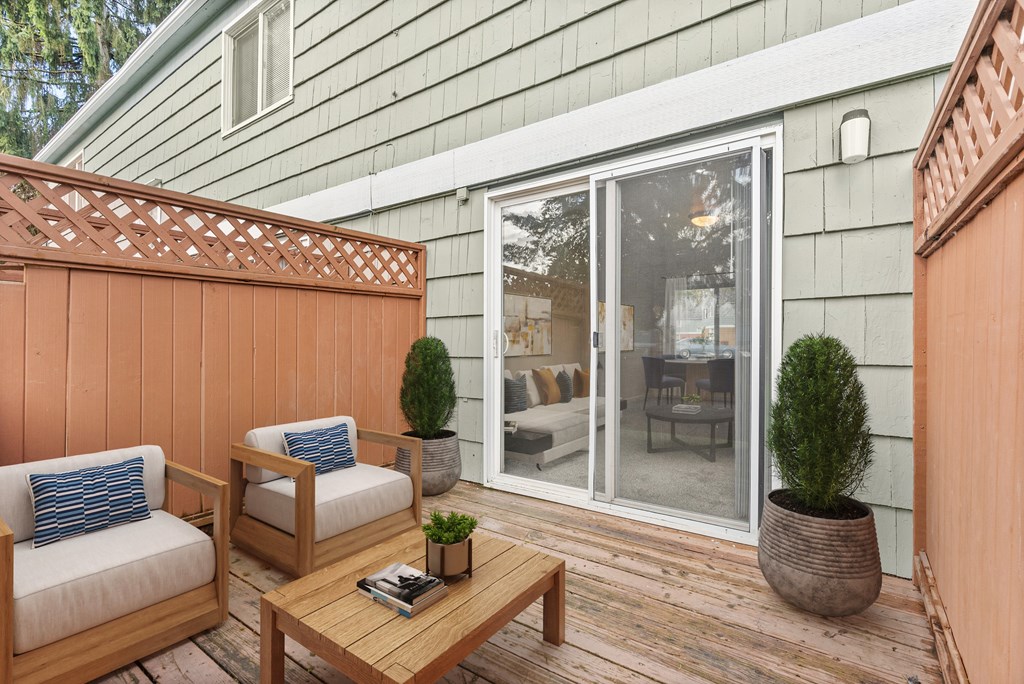A wooden deck with a table and chairs and a potted plant.