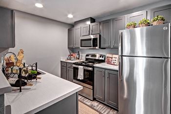 a kitchen with stainless steel appliances and gray cabinets at Deer Creek Apartments, Washington