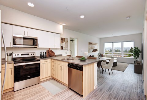 A modern kitchen with wooden floors and stainless steel appliances.
