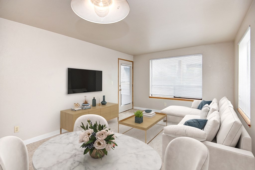 A living room with a white couch, a coffee table, and a flat-screen TV.