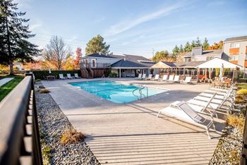 A pool area with sun loungers and a building in the background. at Northpoint Apartments, Washington, 98407