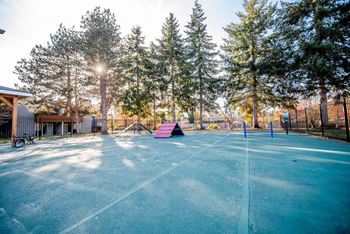 A tennis court surrounded by trees and a fence. at Northpoint Apartments, Tacoma, WA, 98407