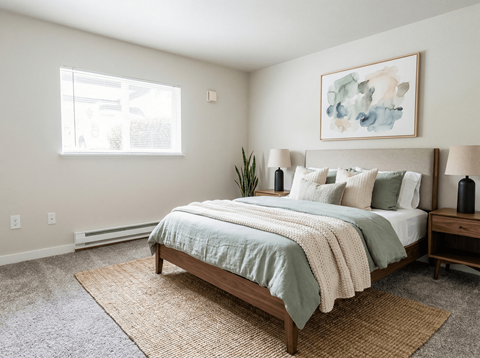 A bedroom with a bed, nightstand, and a painting on the wall.