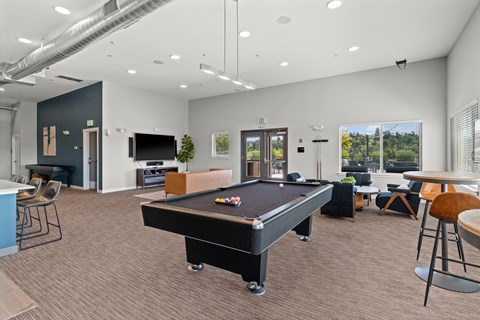 A room with a pool table and a bar area.