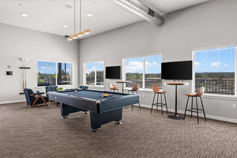 A room with a pool table and bar stools.