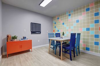 a dining room with a table and chairs and colorful tiles on the wall