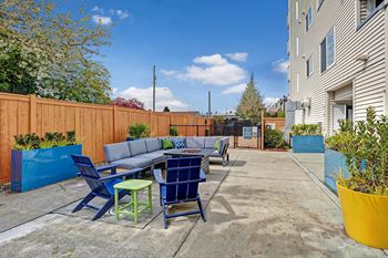 a patio with blue chairs and a table and a blue fence