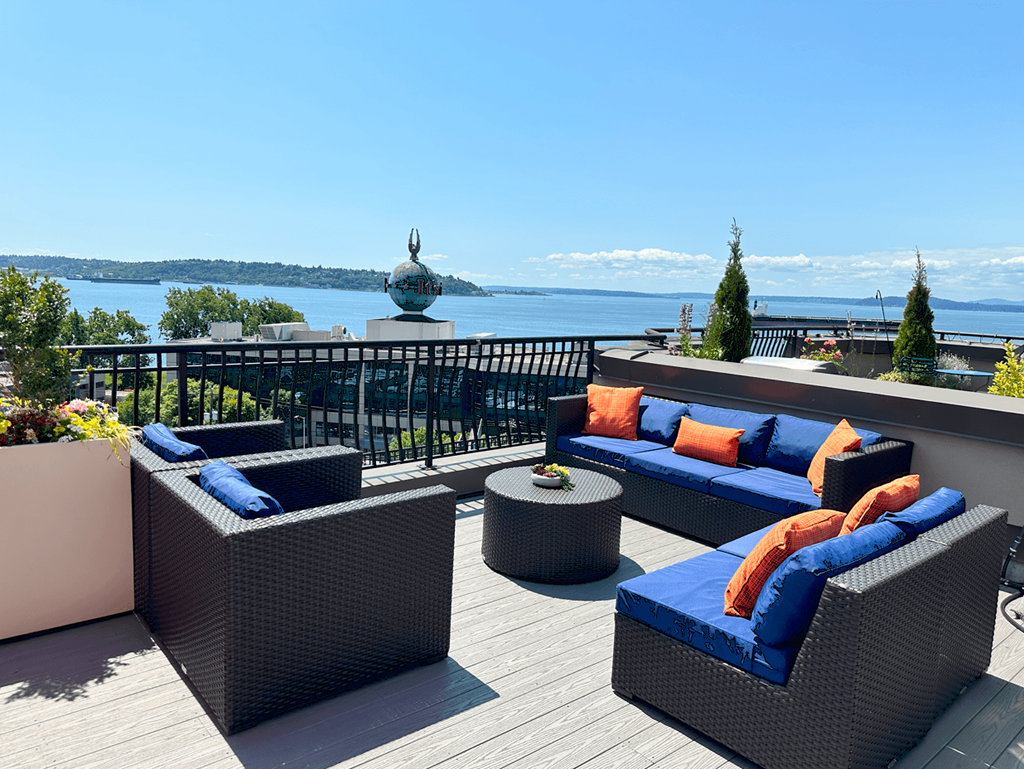 A patio with blue cushions and a view of the water.