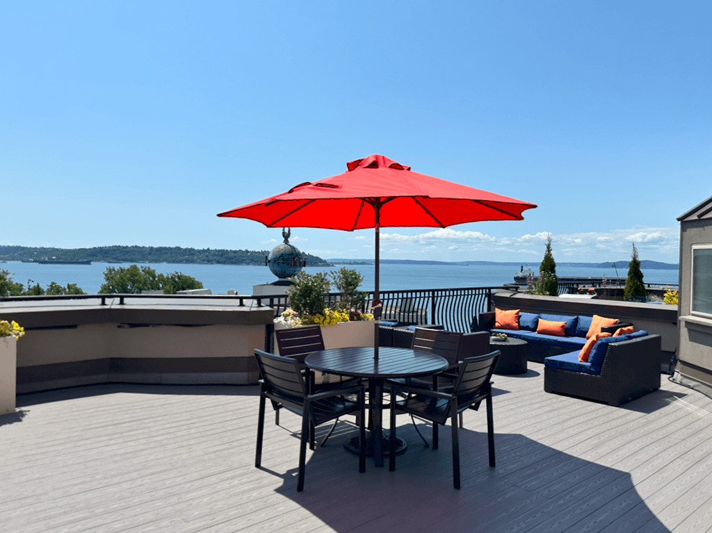 A red umbrella is on a table with chairs around it.