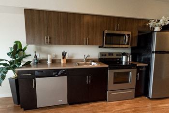 A modern kitchen with dark brown cabinets and stainless steel appliances. at The Platform, Kent, Washington