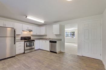 A kitchen with white cabinets and a wooden floor. at The Retreat, Sumner, WA, 98390