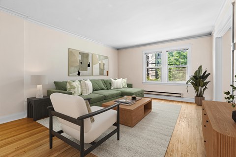 A living room with a green couch, a chair, a coffee table, and a painting on the wall.