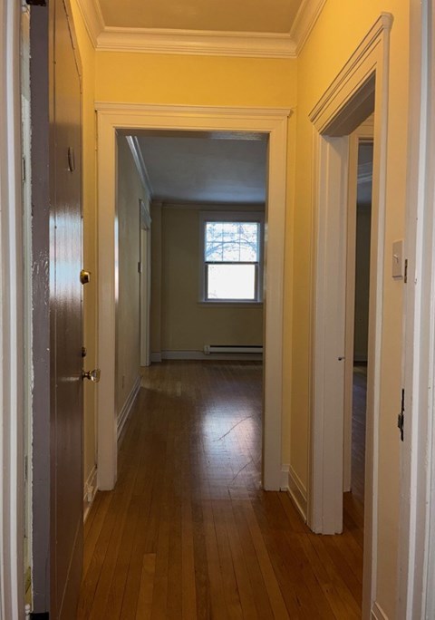 A long hallway with a door on the left and a window on the right.