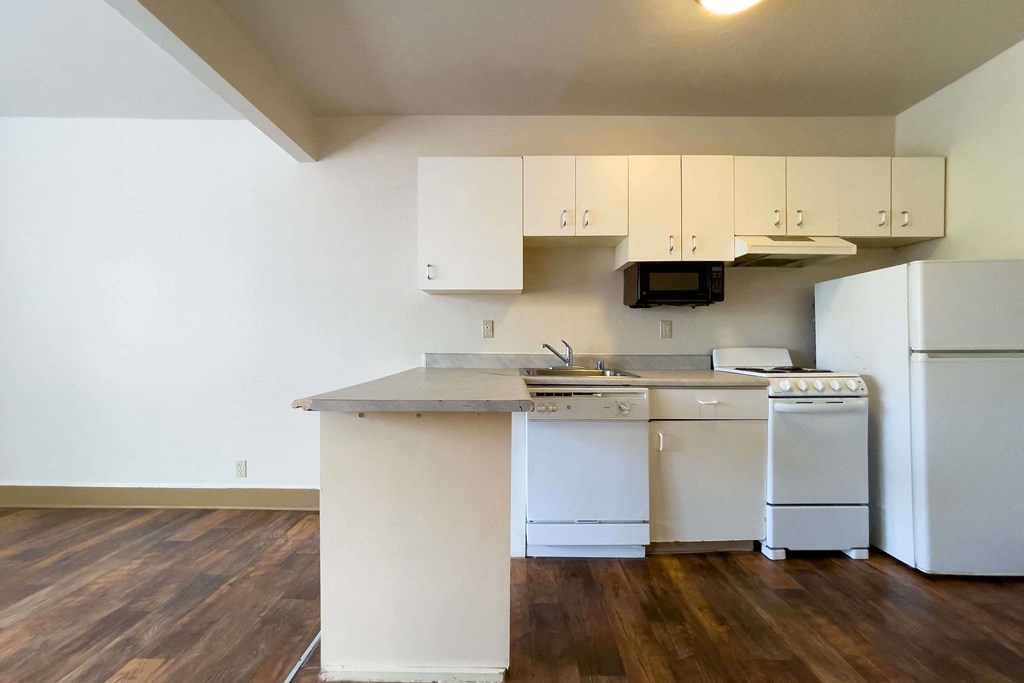A kitchen with white appliances and wooden floors. at Zindorf, Seattle, 98104