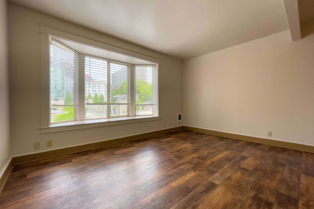 A room with wooden floors and a large window with blinds. at Zindorf, Seattle, WA