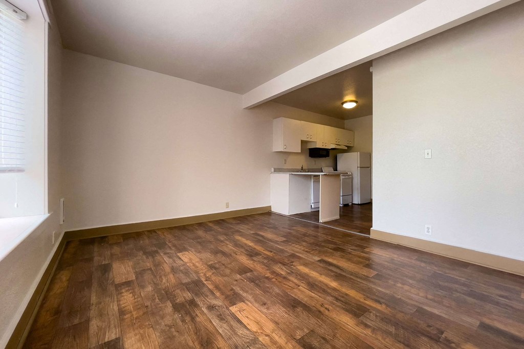 A room with wooden flooring and a kitchen area in the background. at Zindorf, Seattle, WA, 98104