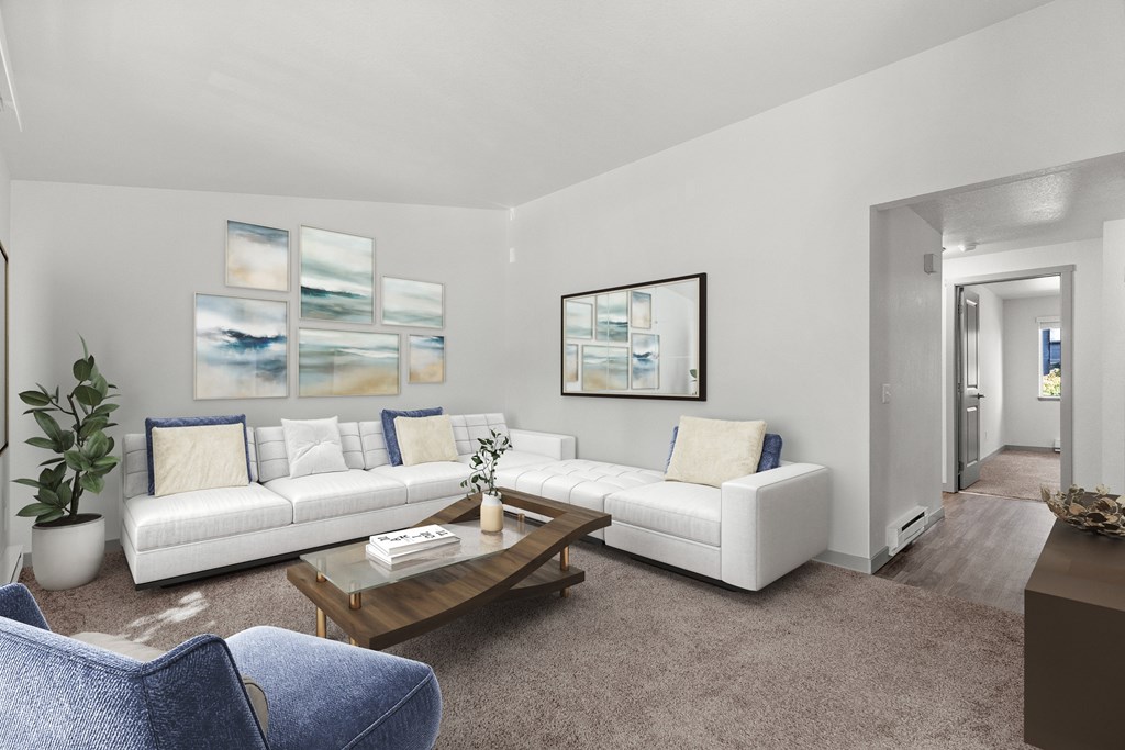 A living room with a white couch, a blue chair, and a painting on the wall.