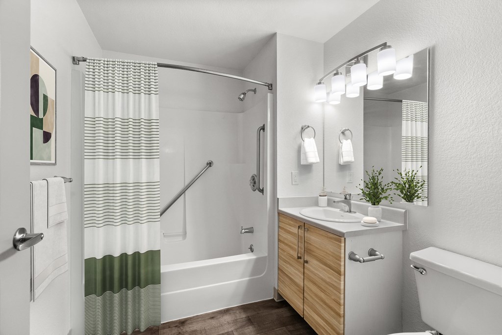 A white bathroom with a wooden vanity and a white bathtub.