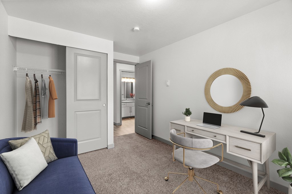 A well-lit room with a blue sofa, a desk with a laptop, and a mirror on the wall.