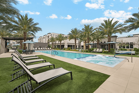 A pool surrounded by palm trees and lounge chairs.
