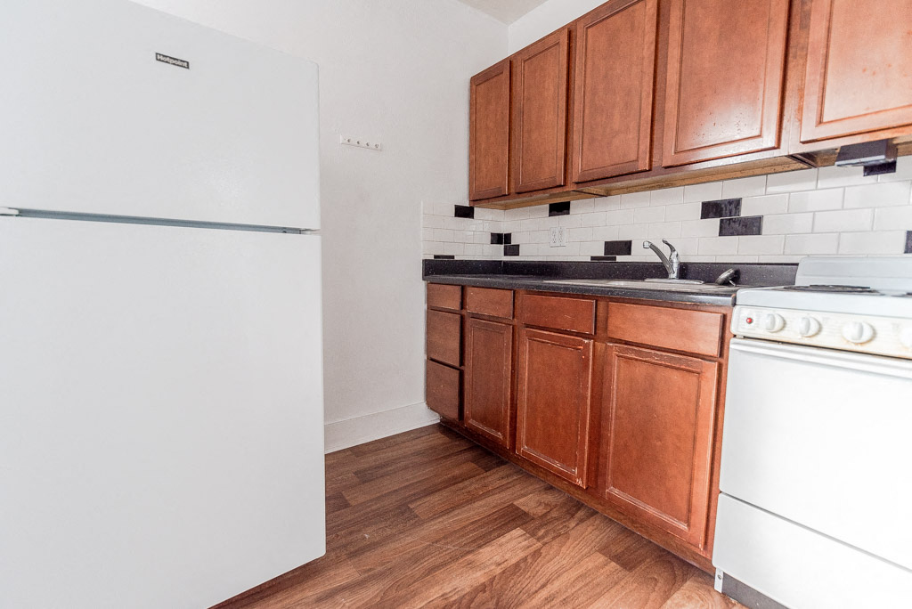 A kitchen with wooden cabinets and a white fridge.