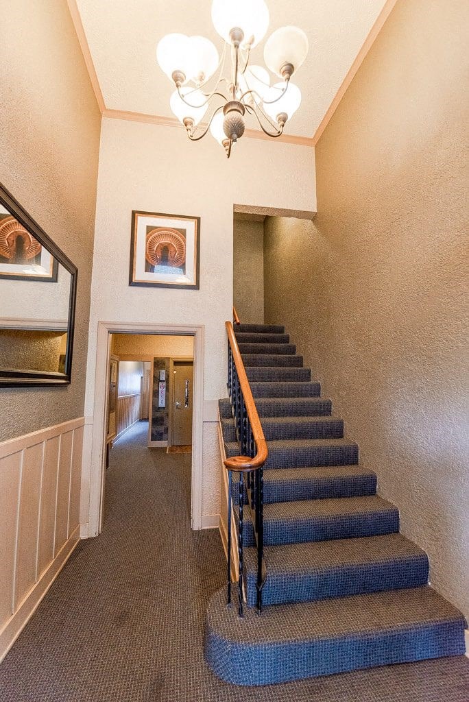 A staircase with a wooden handrail and a chandelier hanging from the ceiling. at Edwards on Fifth, Washington