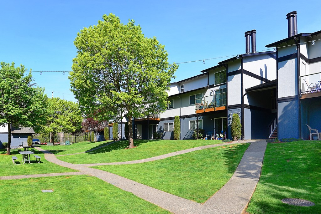 a grassy area with trees and buildings in the background