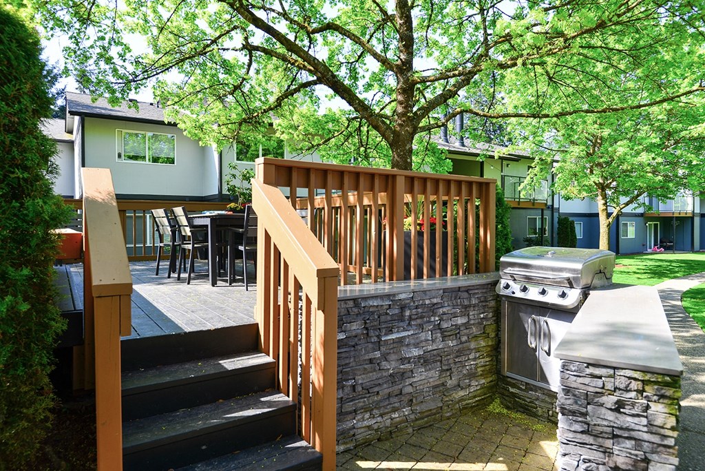 a deck with a grill and a stone wall