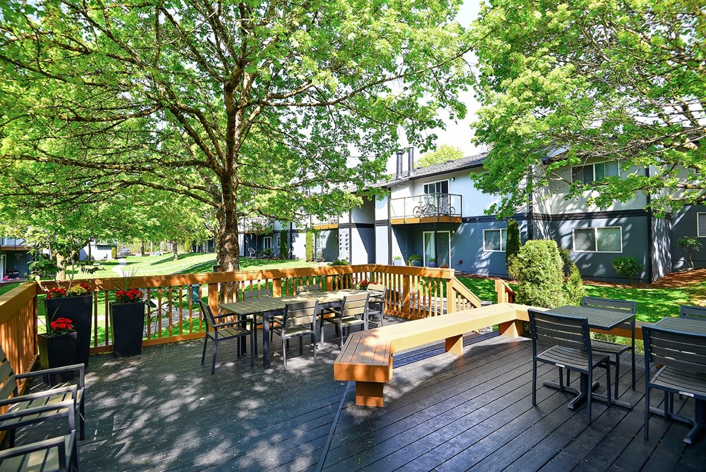 a large wooden deck with a bench and tables
